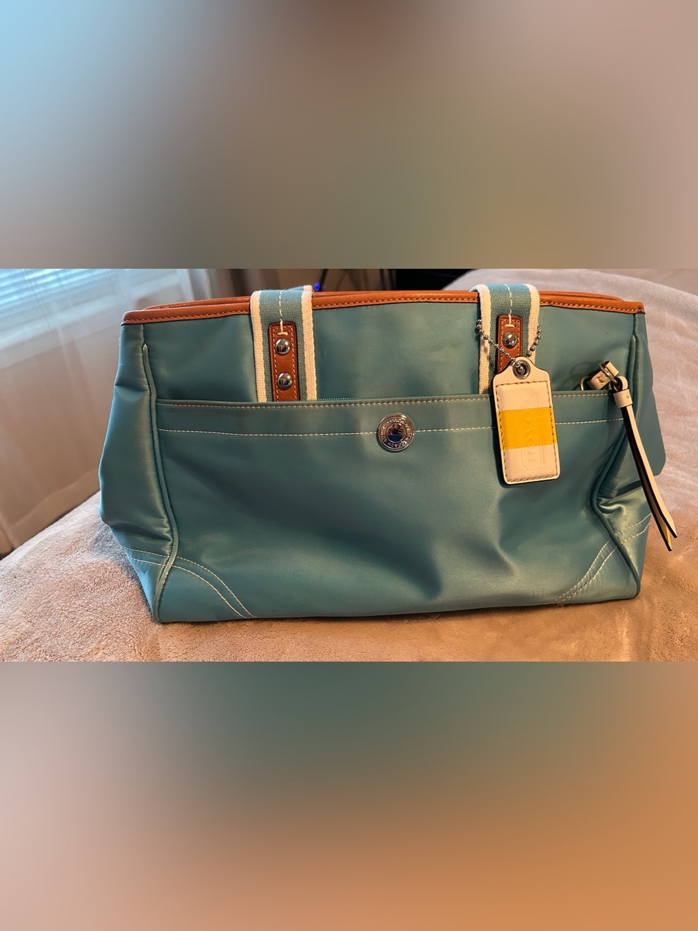 Coach Hampton Weekend Small Tote features a bright aqua blue satin finish